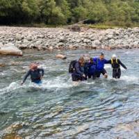 Linking arms, crossing the Deception River over Goat Pass. | Adventure South NZ