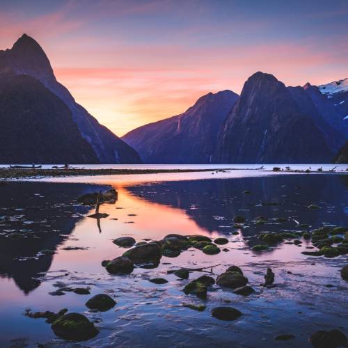 Sun setting over Mitre Peak and surrounding mountains in Milford Sound