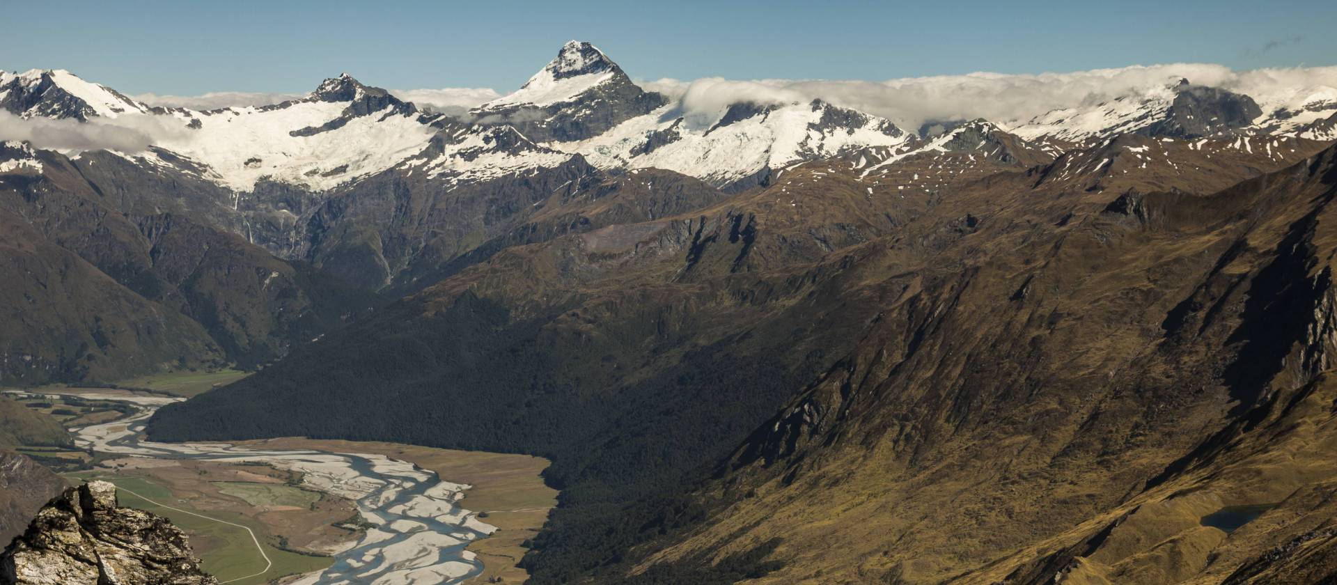 Trekker on Buchanan peak with Mount Aspiring behind, walking above Matukituki valley, near Lake Wanaka | Colin Monteath