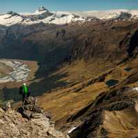 Trekker on Buchanan peak with Mount Aspiring behind, walking above Matukituki valley, near Lake Wanaka | Colin Monteath