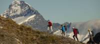 Trekkers on Buchanan peak with Mount Aspiring behind, walking above Matukituki valley, near Lake Wanaka | Colin Monteath