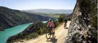 Two cyclists ride the Roxburgh Gorge Trail on a Gravel Bike and an eBike, with McKenzies Beach and Knobby Range in the background | Geoff Marks