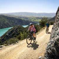 Two cyclists ride the Roxburgh Gorge Trail on a Gravel Bike and an eBike, with McKenzies Beach and Knobby Range in the background | Geoff Marks